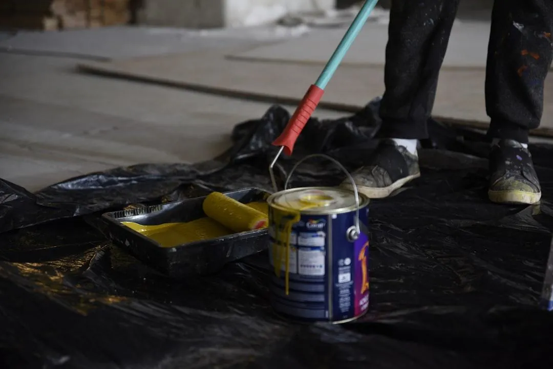 Paint roller and open paint can on protective plastic sheeting