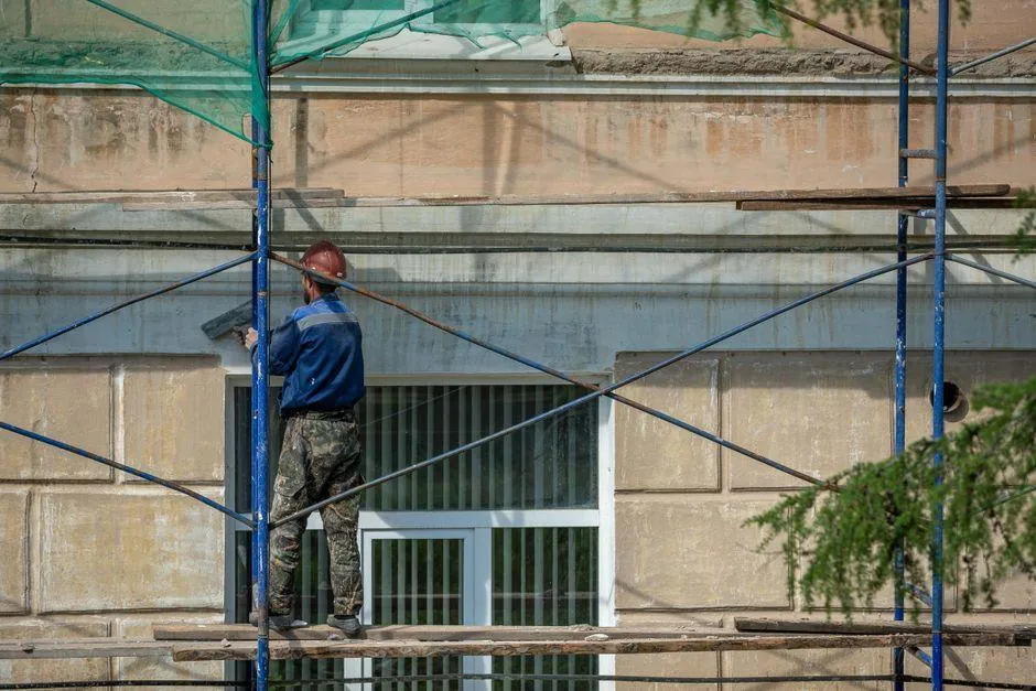 Painter working on scaffolding along a building exterior