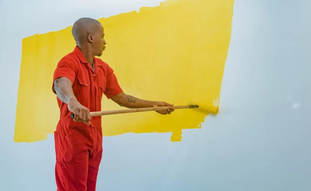 Painter rolling yellow paint onto a wall